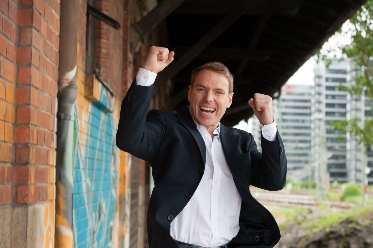 Christoph Kleinbeck celebrating with raised fists to represent success and peak performance in Elite Coaching.